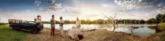 Panoramic of a French couple enjoying refreshments at the side of a lake in Phinda