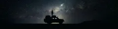 Silhouette of a person standing on the roof of their vehicle staring at the stars in sossusvlei
