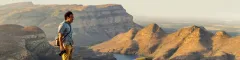 Man standing with a view of the Blyde River Canyon hills and mountains